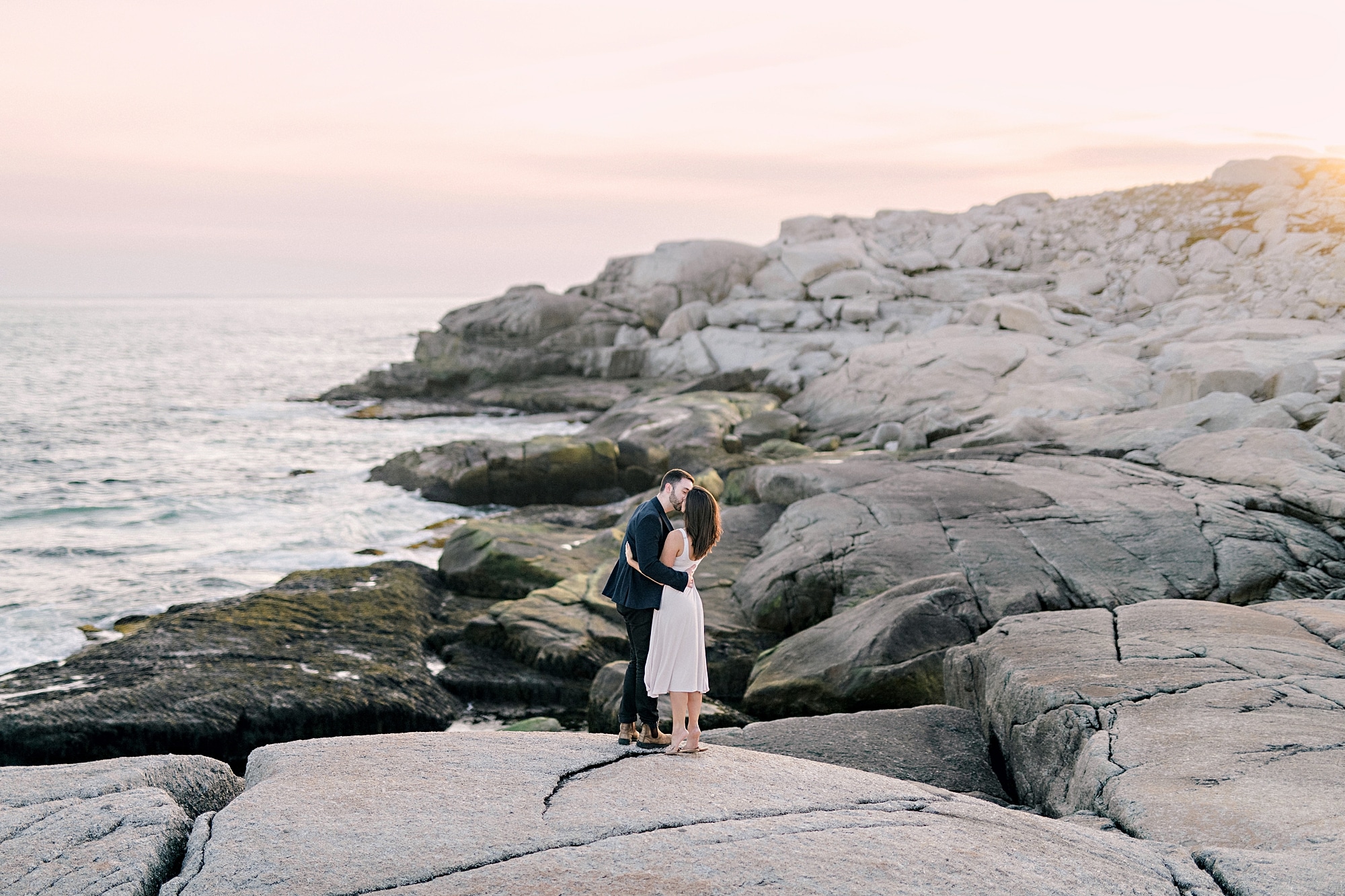 engaged couple on cliff overlooking the ocean