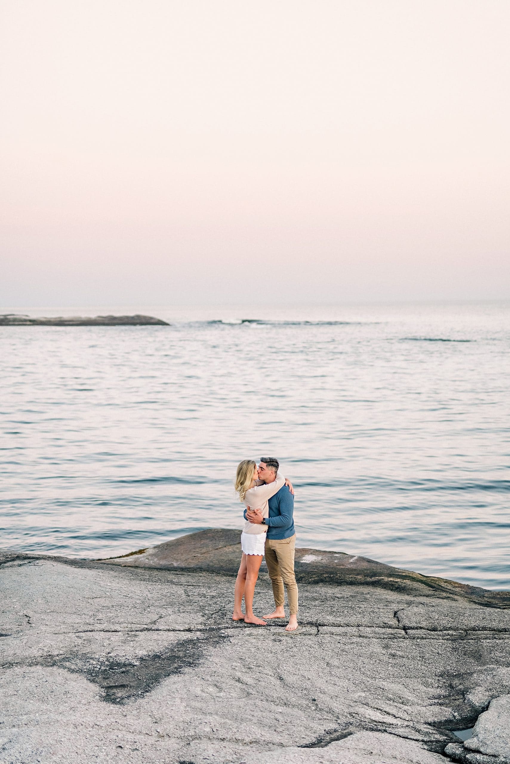 couple embracing on the rocks overlooking the sunset