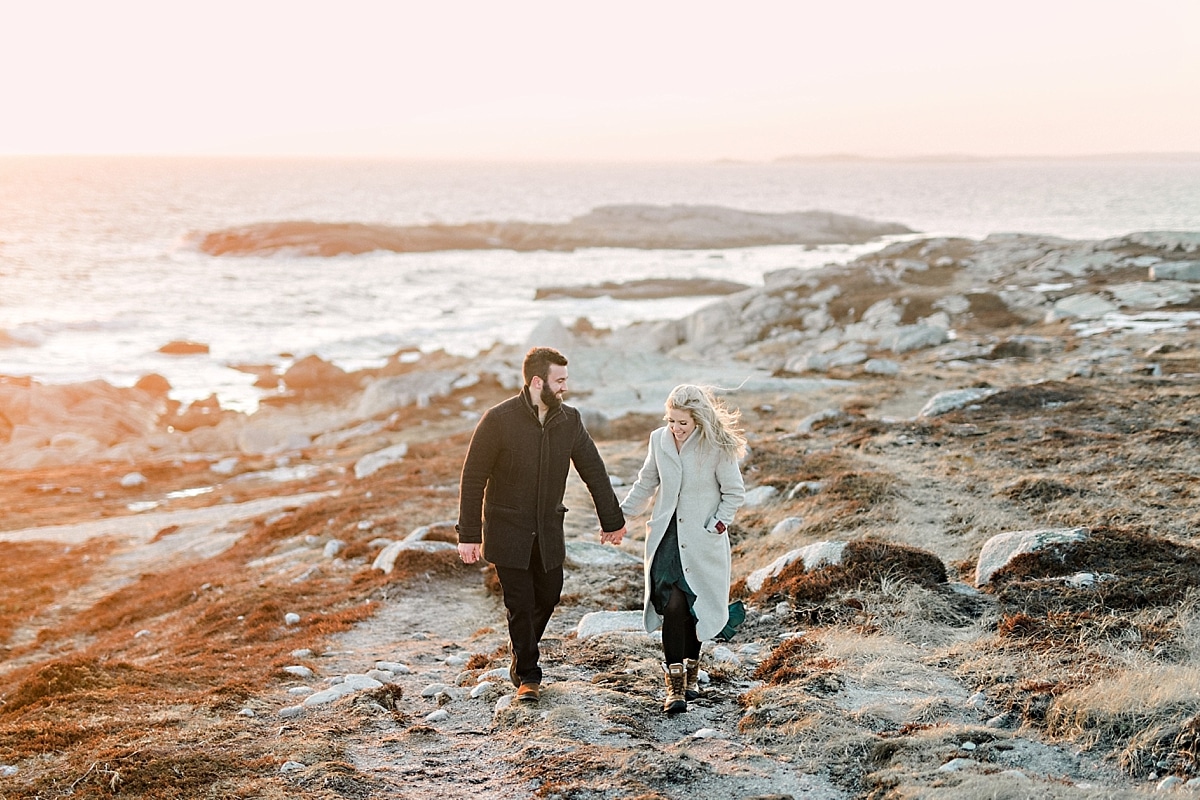 girl and guys walking on rocky cliffs by the ocean at sunset