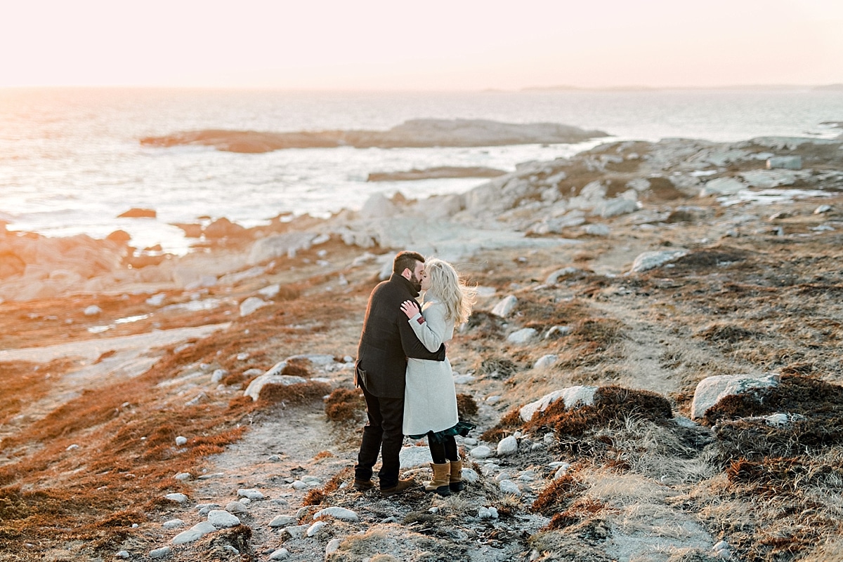 girl and guys hugging on rocky cliffs by the ocean at sunset