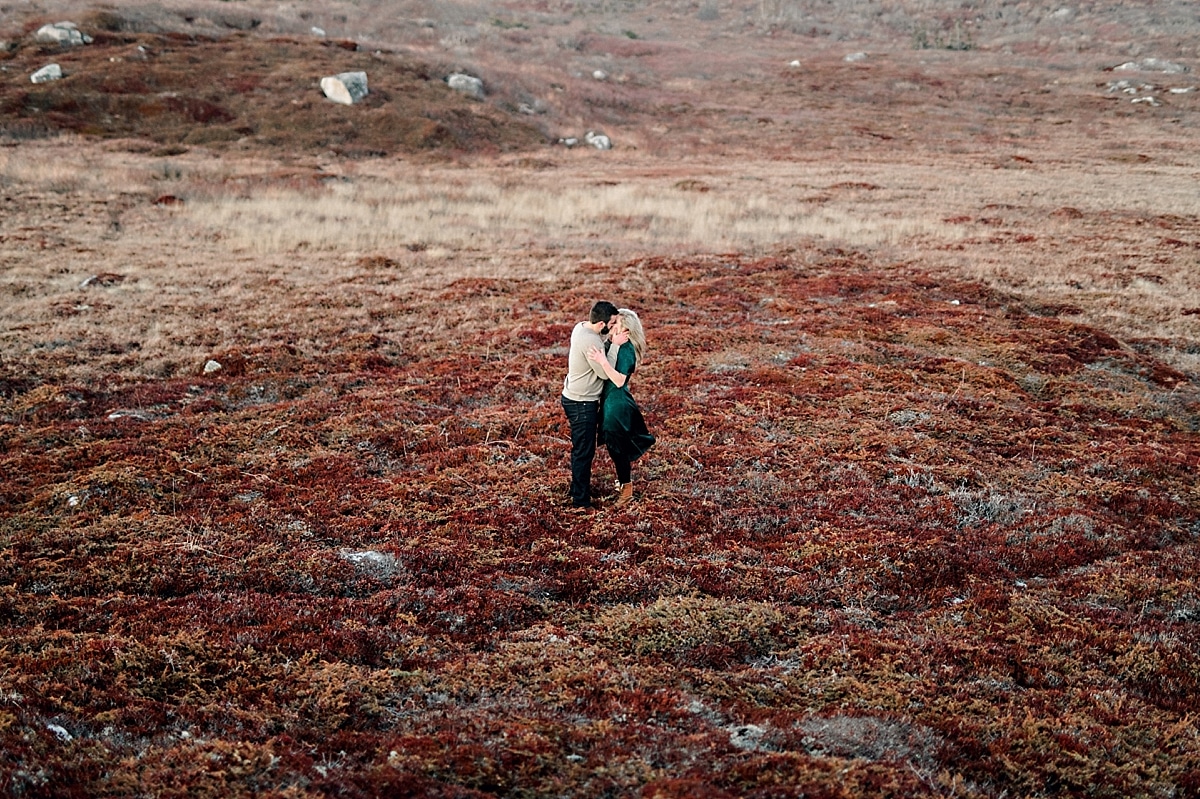 couple standing in vibrant red field in the fall