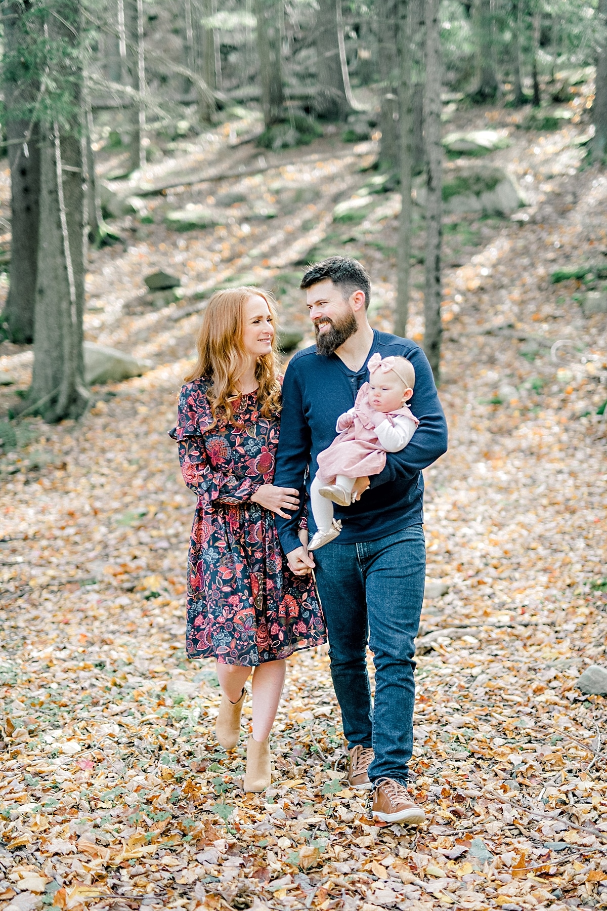 young family walk with baby through forest in the fall