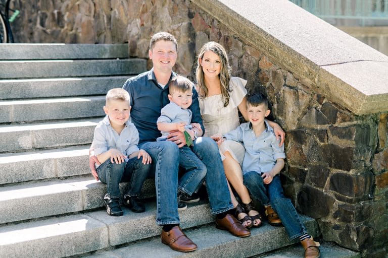 mom and dad with three boys smiling for camera during family photo shoot