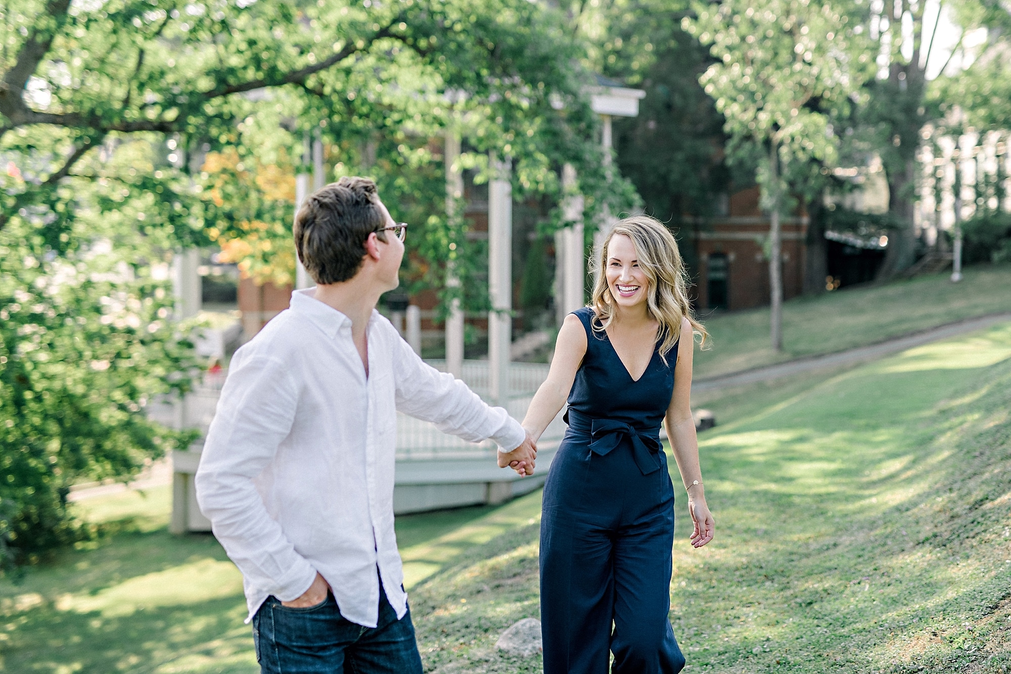 couple running in park with gazebo during engagement photoshoot