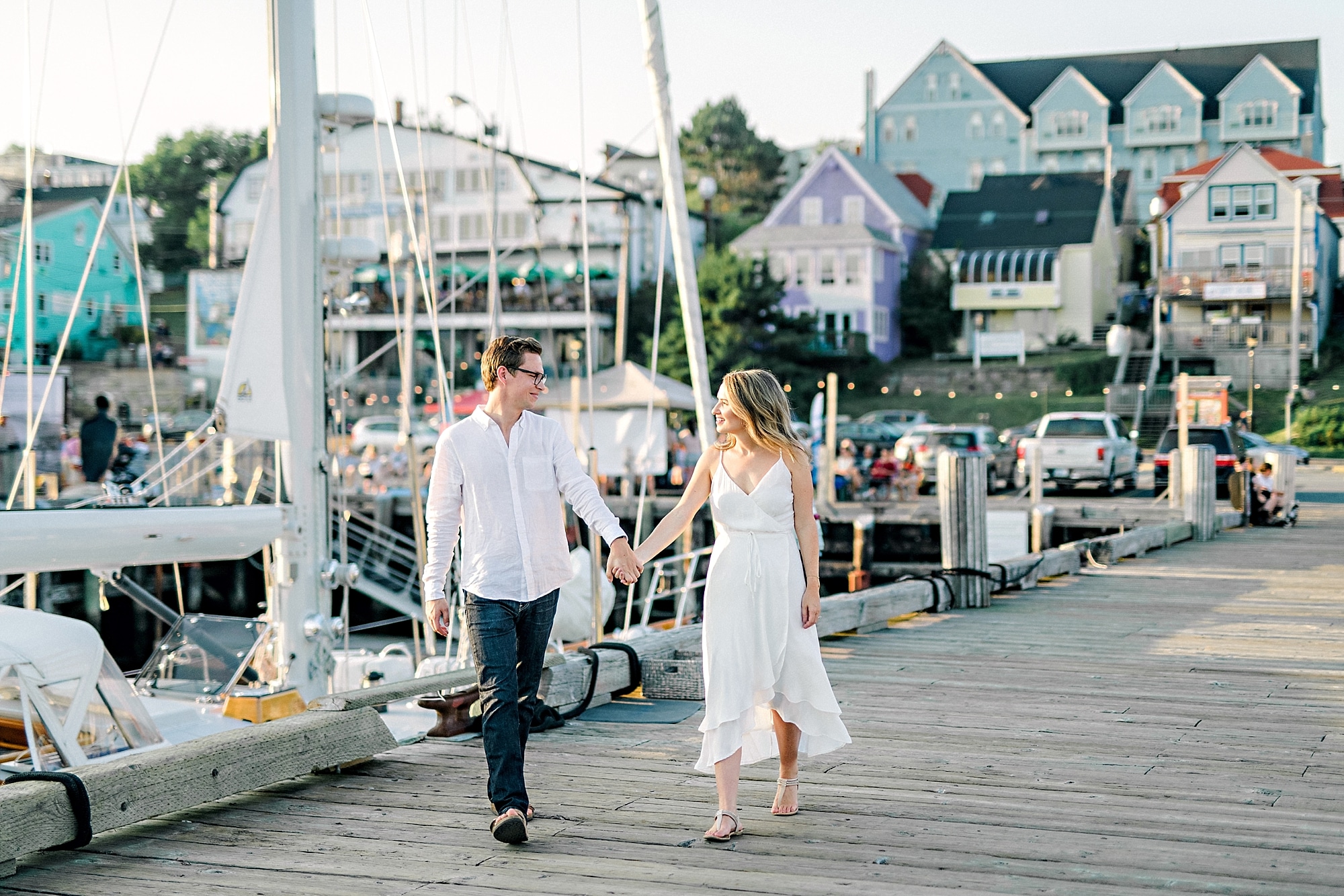 engaged couple walking by the sailboats on a dock in lunenburg